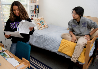 Two students in their Residence Hall looking at a paper