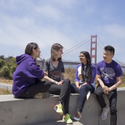 students sitting smiling with the golden gate bridge behind them