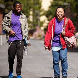 Two Students are walking side by side having a conversation and laughing